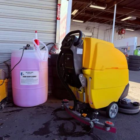 Titan floor cleaner drum next to a yellow floor scrubber